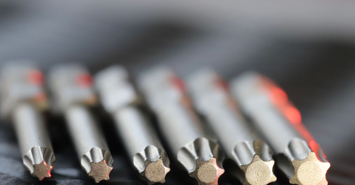 Macro shot of metal precision drill bits with star-shaped tips in a row, emphasizing detail and craftsmanship.